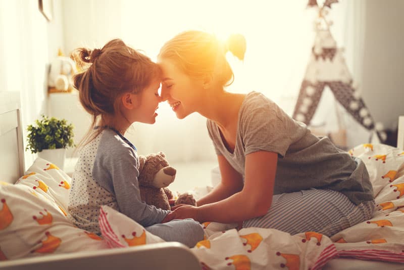 mother cuddling with little daughter on the bed