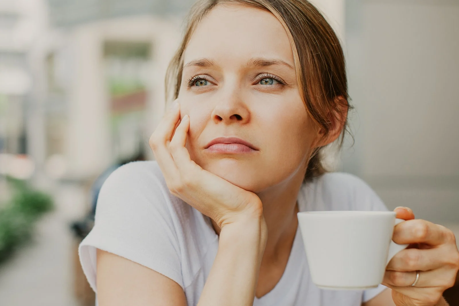 pensive young beautiful woman drinking coffee outdoors