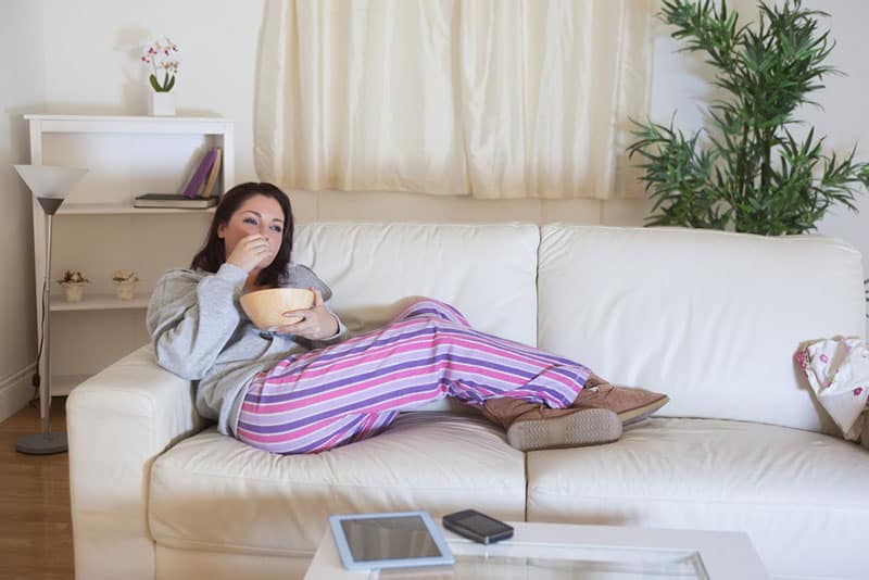 relaxed woman in nightwear sitting on couch at home