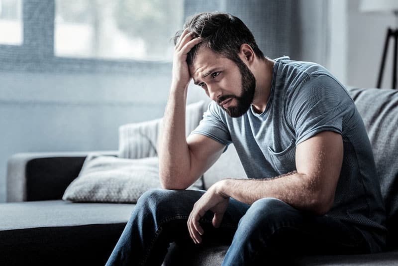 hombre triste sentado en un sofá