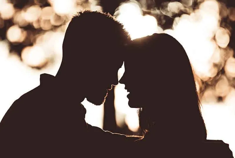 silhouette of couple puts heads on each other outside