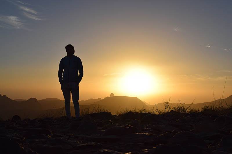 silhouette of man watching sunset