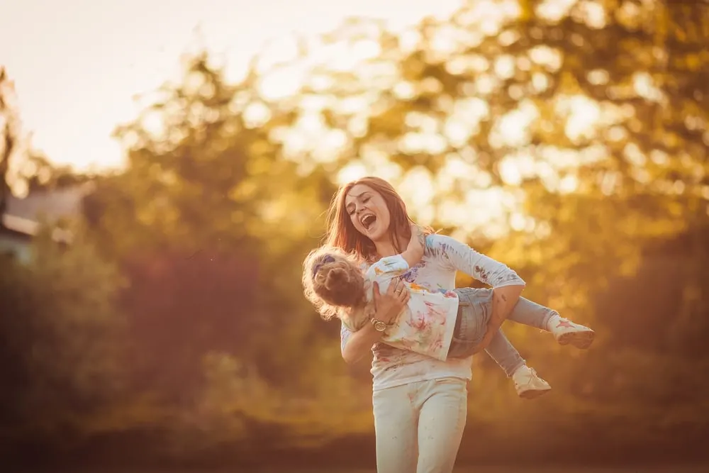 the woman carries the child across the field and laughs