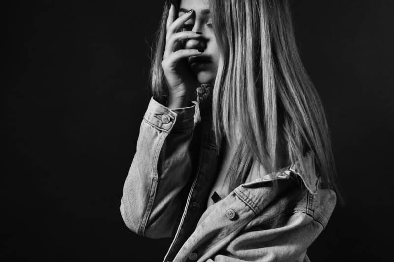 woman in denim jacket covering her face