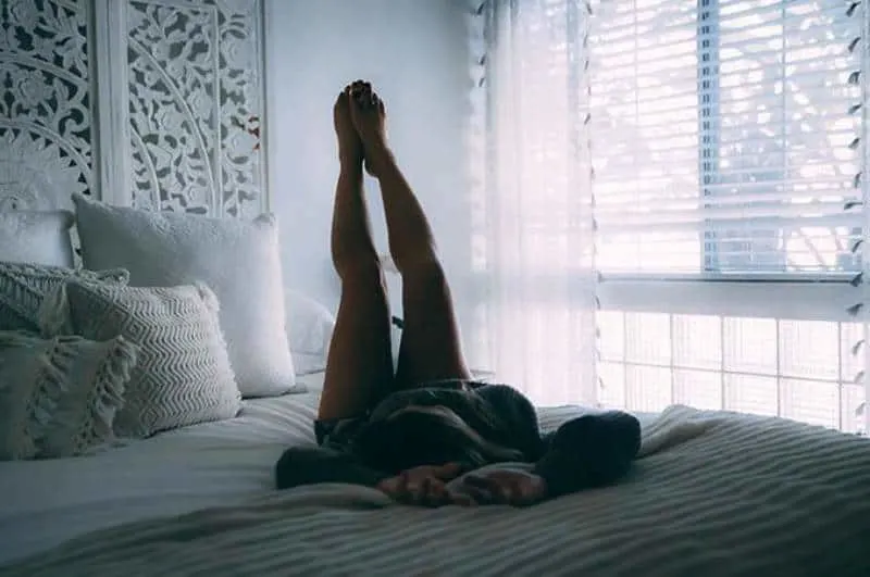 woman lying on bed and raising her legs