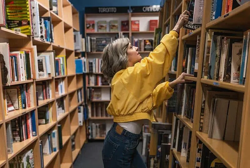 woman reaching a book on the shelf