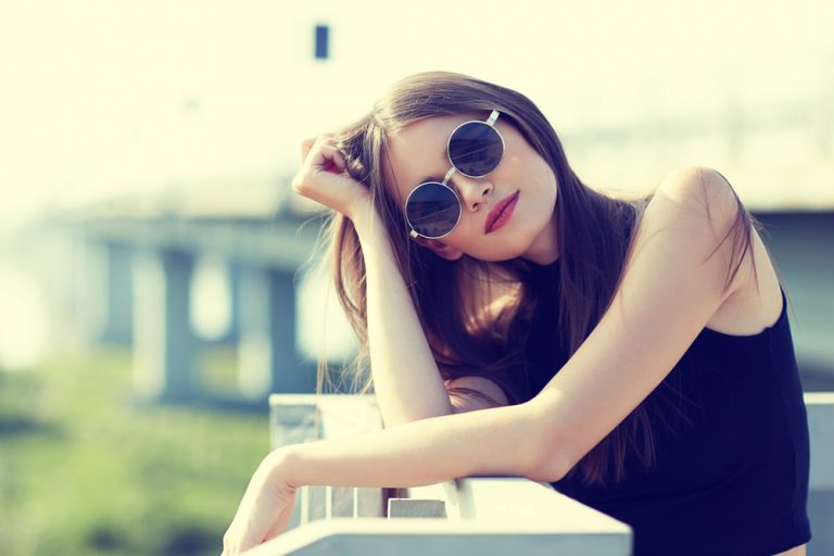 beautiful brunette with sunglasses standing on the terrace