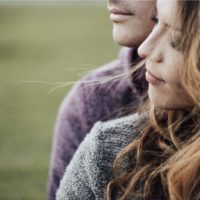 Young loving couple outdoors sitting on grass