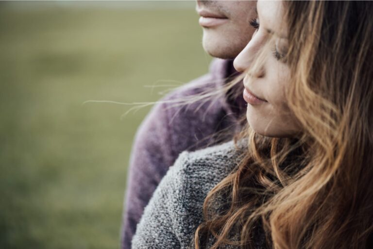Young loving couple outdoors sitting on grass