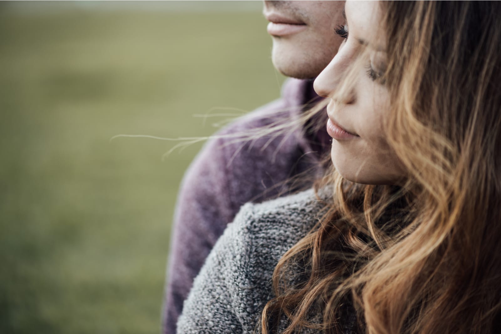 Young loving couple outdoors sitting on grass