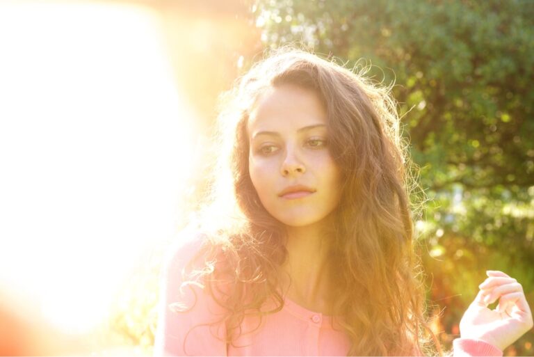 Portrait of attractive woman with long hair outside in bright sunlight