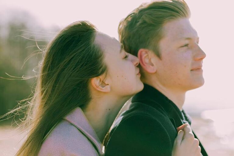woman hugs man from back outdoors
