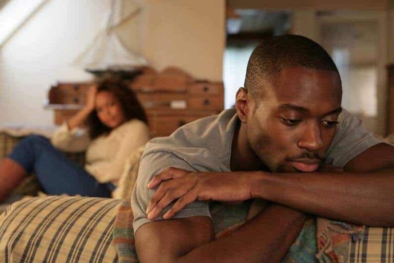 worried man sitting while her girlfriend sitting behind him