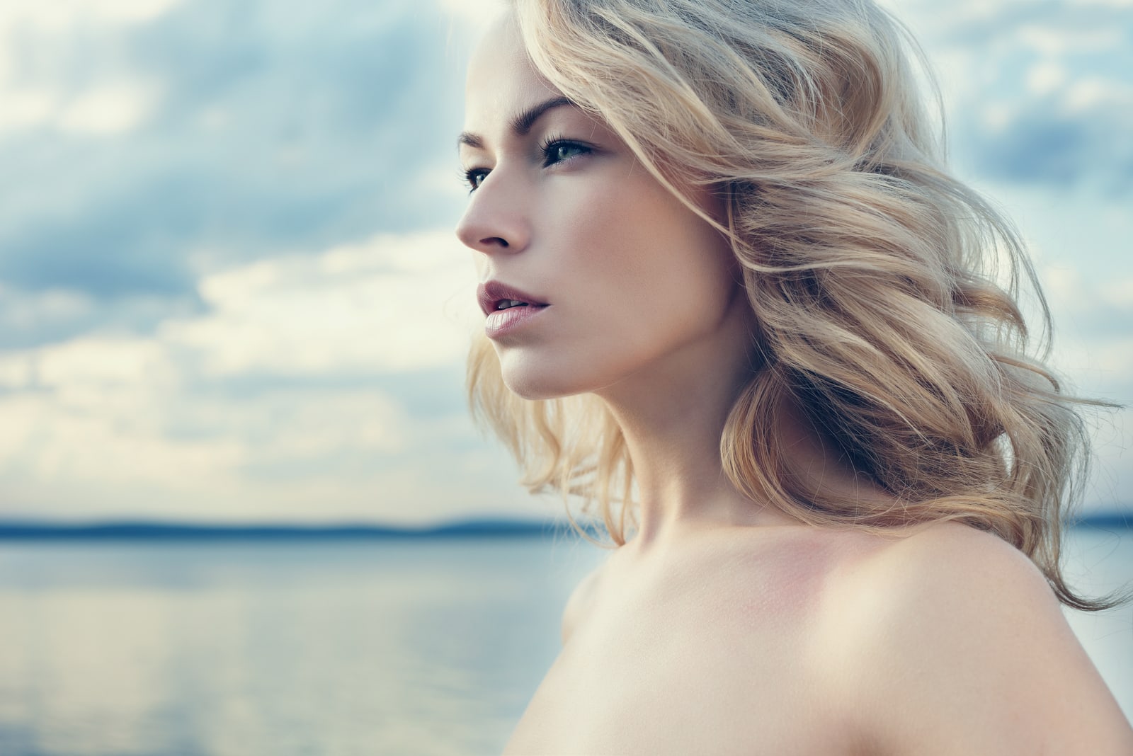 Beautiful young blond woman outdoors portrait near the lake