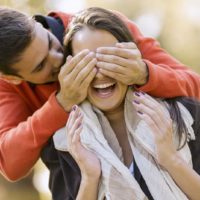 homem feliz a pôr as mãos nos olhos de uma mulher