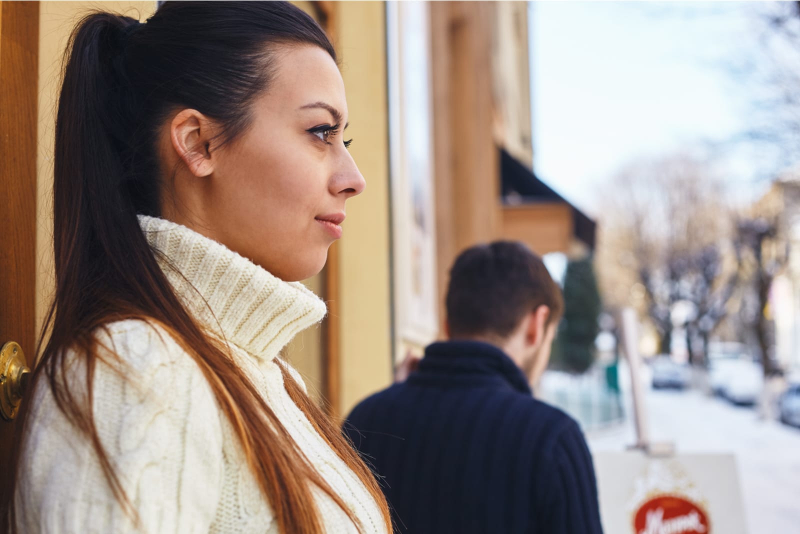 Immagine di una ragazza, in piedi fuori dal caffè, con lo sguardo rivolto altrove