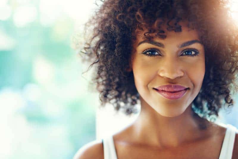 Retrato de uma jovem negra sorridente com um facho de luz solar