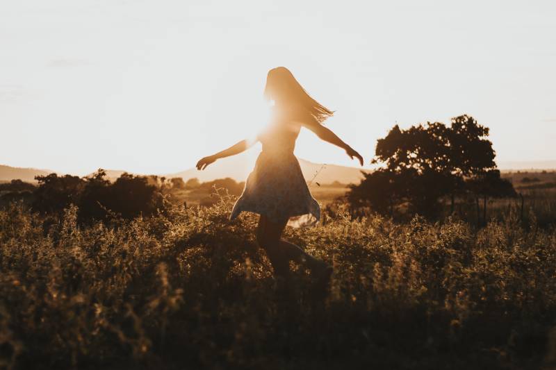 Silhouette of the woman dancing in the middle of the meadow