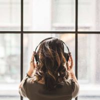 vista trasera de mujer con auriculares y mirando al exterior