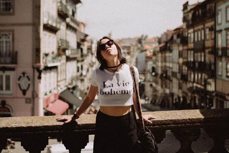 a woman stands on a bridge with glasses on her head