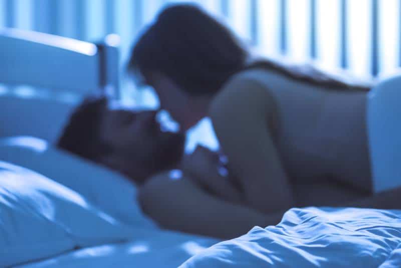 The young couple kiss in bed. Night time