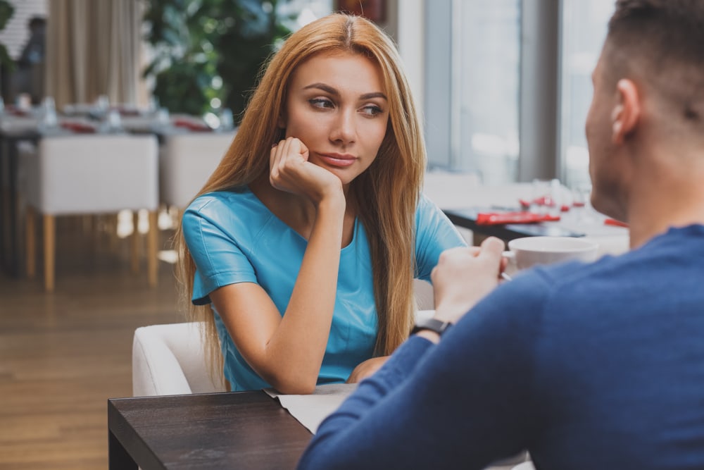 a beautiful blonde sits with a man in a cafe and thinks