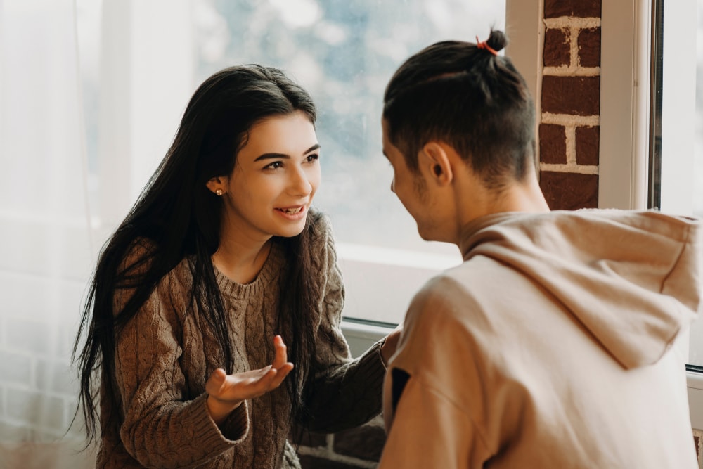 um jovem casal à janela a conversar