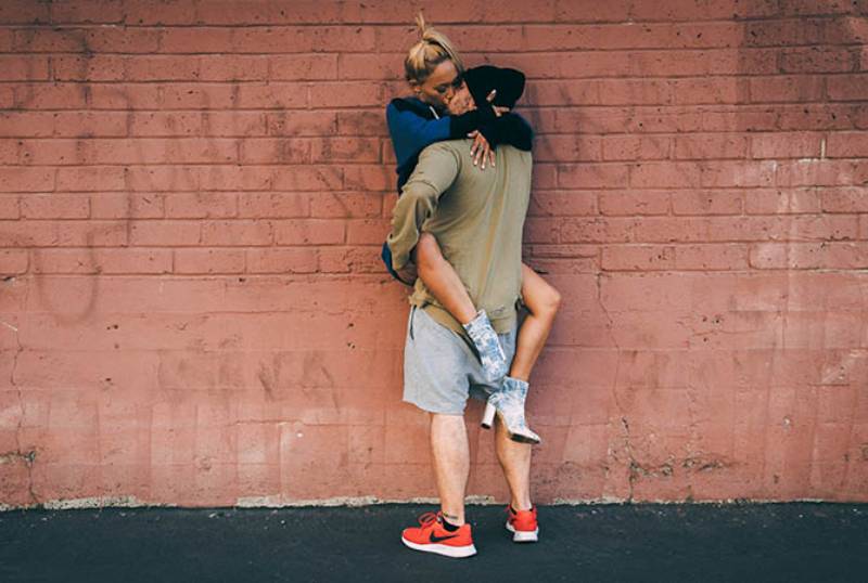 couple kisses outside in front of wall