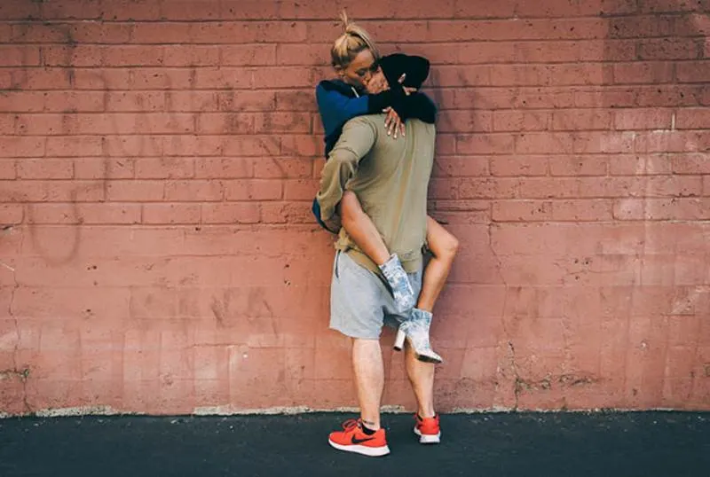 couple kisses outside in front of wall