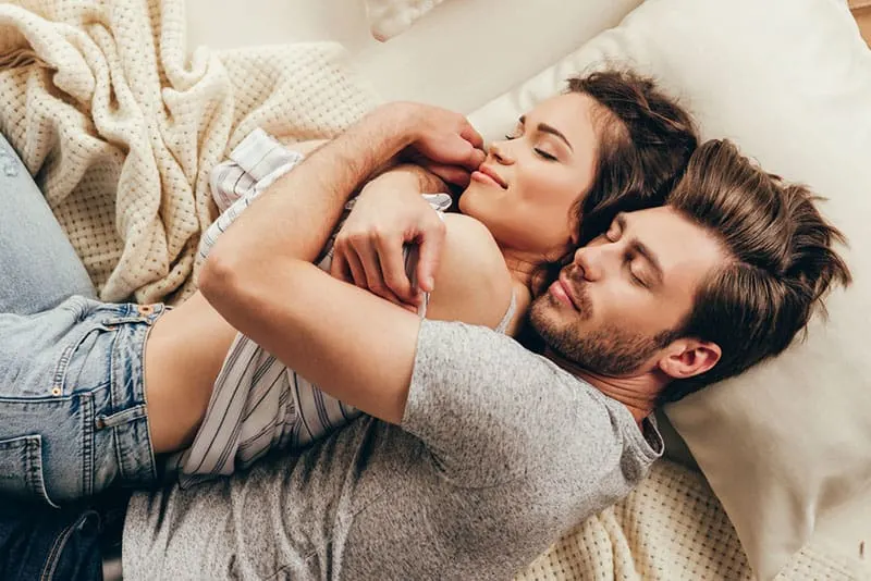couple laying on bed in hug with closed eyes