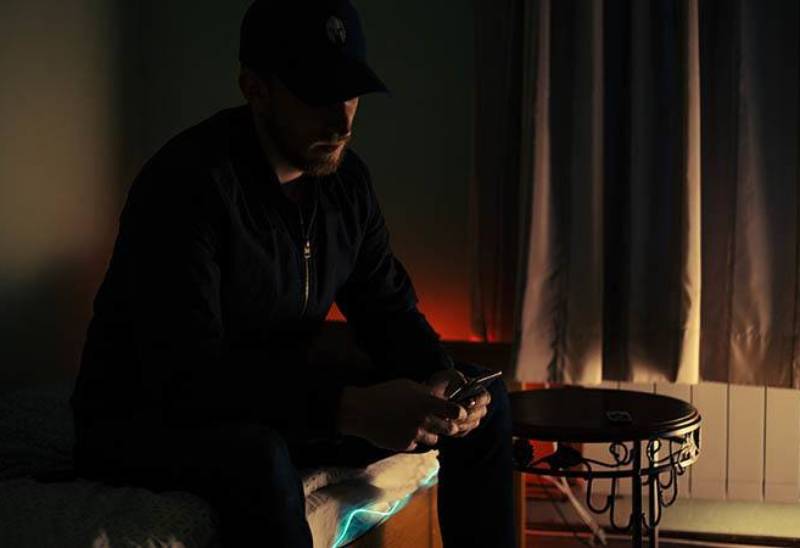 foto scura di un uomo che digita sul suo telefono in casa