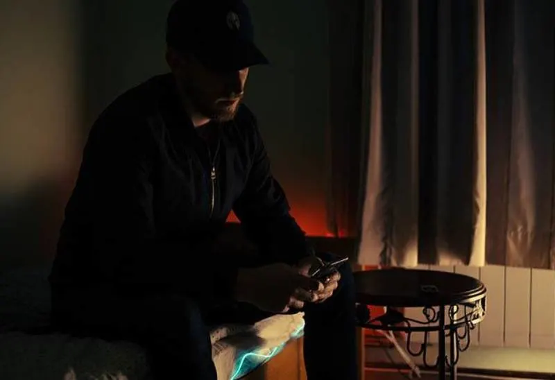 dark photo of man typing on his phone at home
