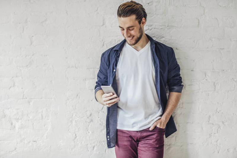 handsome smiling young caucasian man typing on his cell phone.
