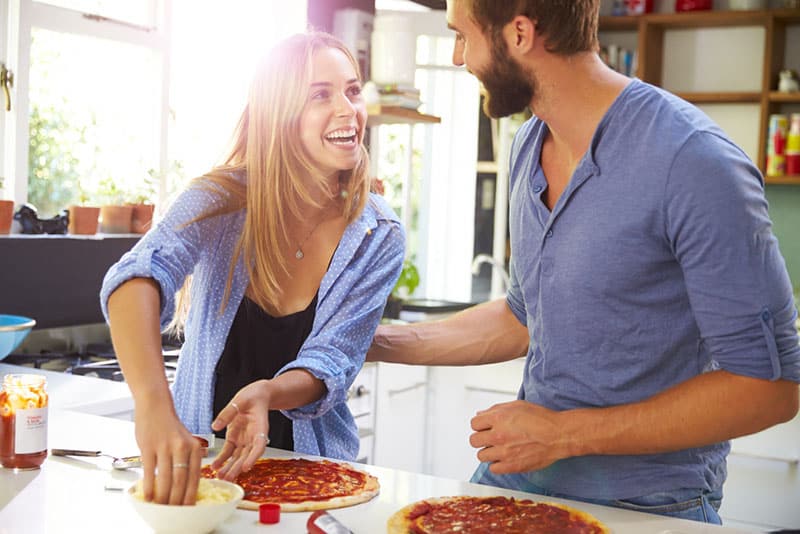 happy couple in the kitchen making pizza