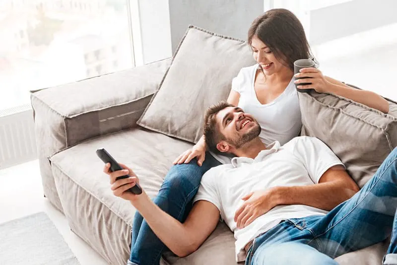 happy man laying in woman lap on the couch
