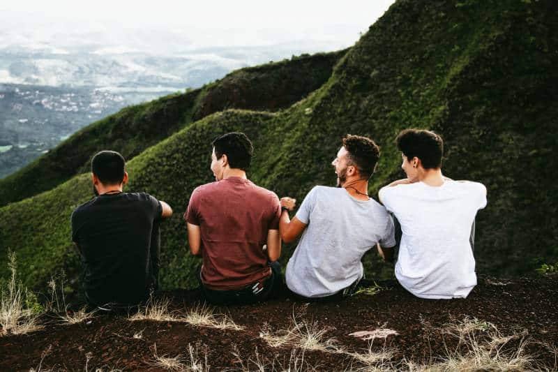 amici maschi che ridono e siedono sulla collina