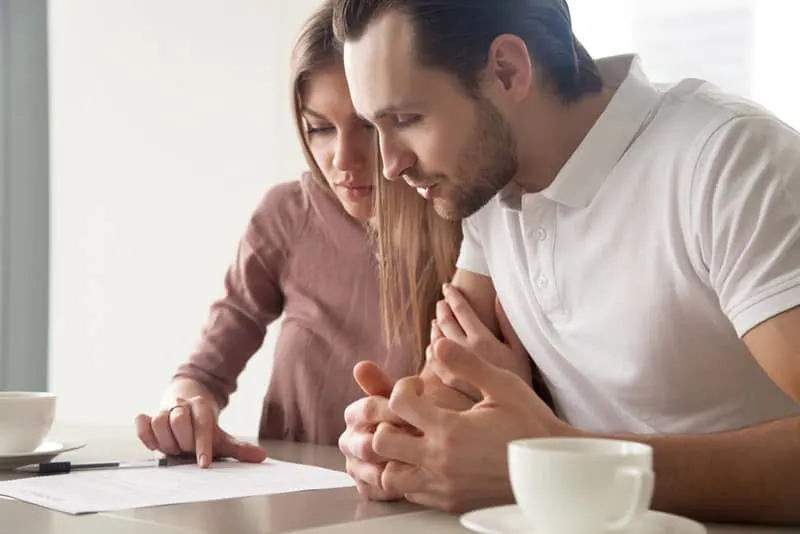 man and woman looking at paper on table while sitting at home