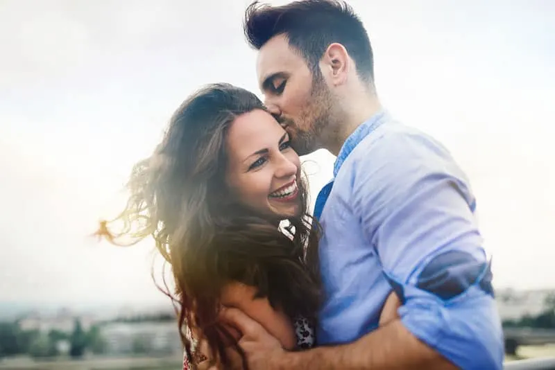 man kissing smiling woman outdoor