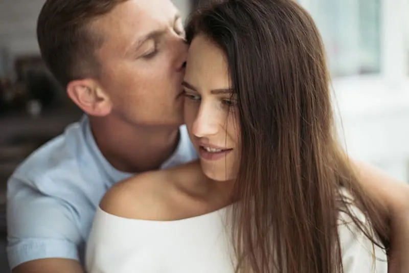 man kissing woman in head