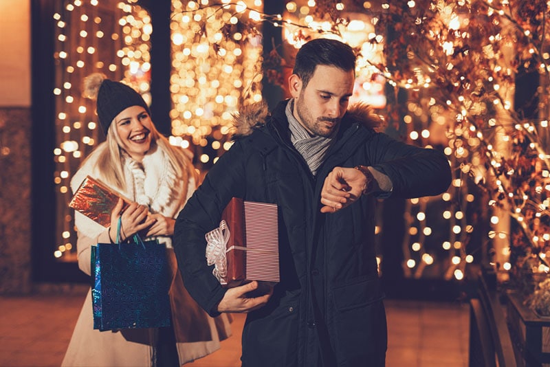 man waiting for woman with christmas gifts
