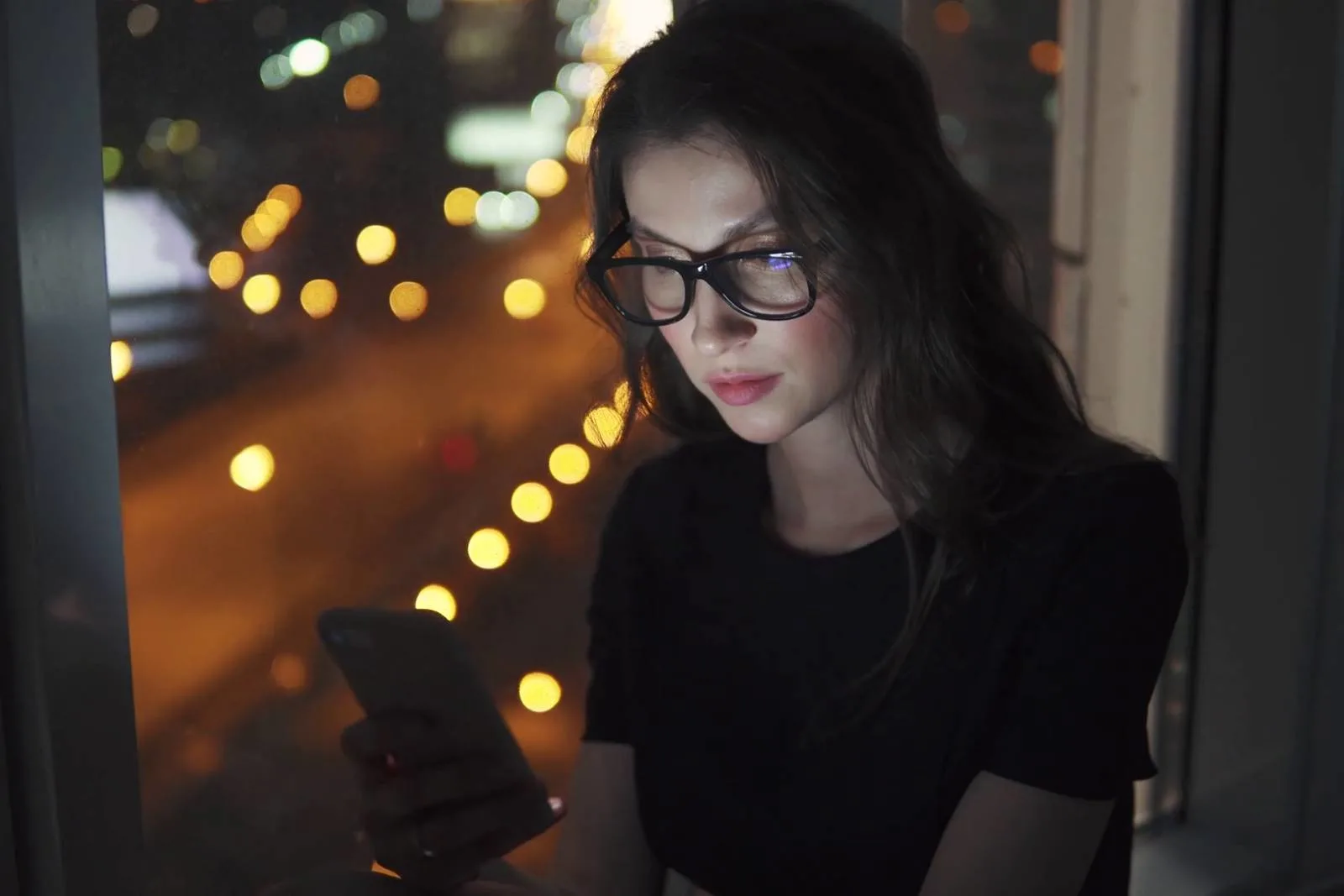 portrait of a young girl in the light of the smartphone screen