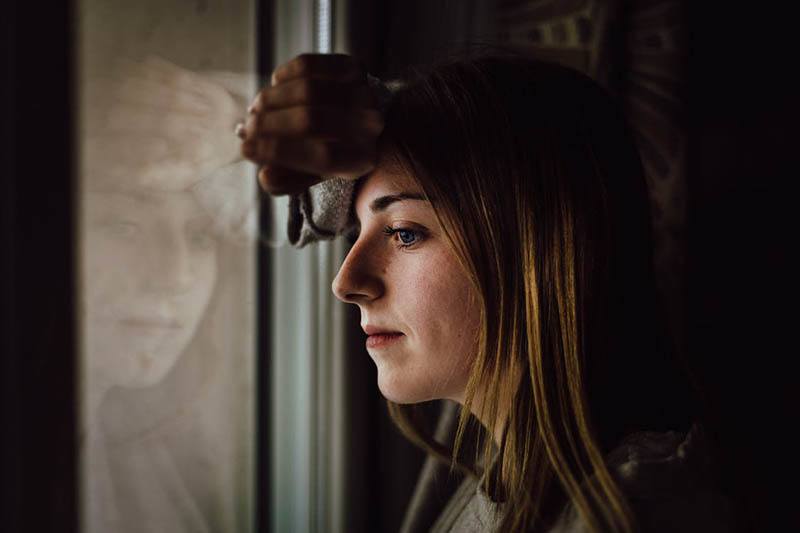 sad woman looking through window