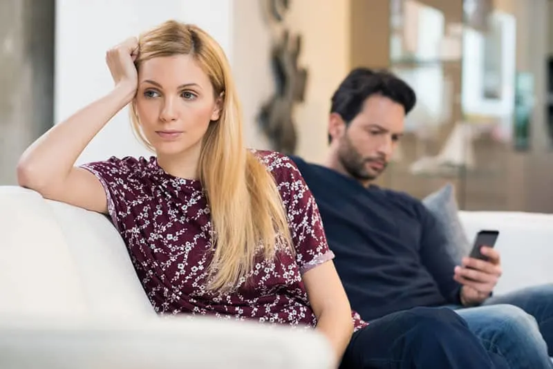 sad woman sitting apart from boyfriend who is typing