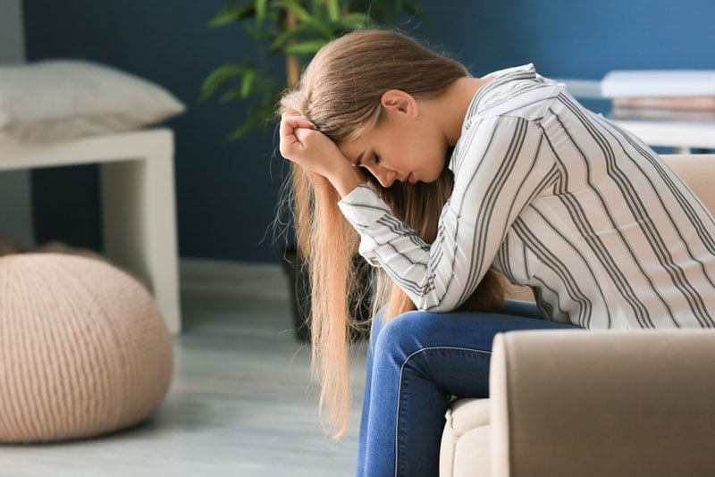 mujer triste sentada en el sofá preocupada