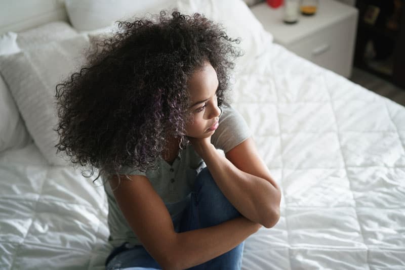 sad young woman sitting on bed