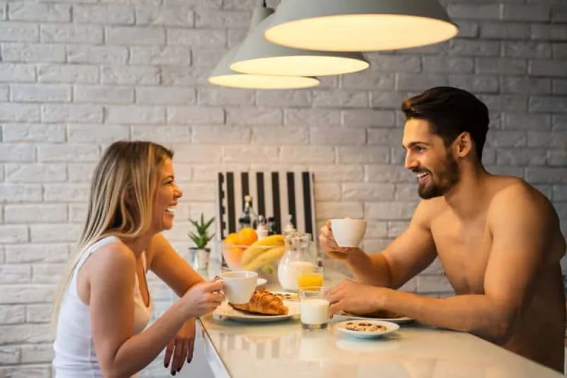 smiling man and woman talking while holding cup of coffee