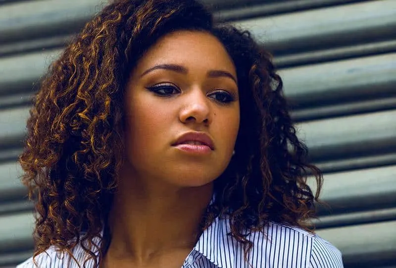 thoughtful afro woman wearing shirt outside