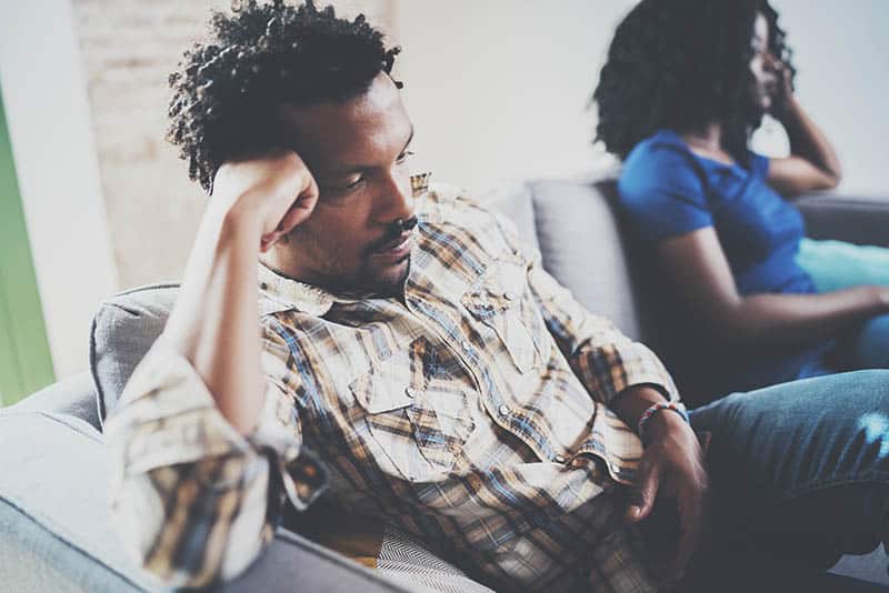 thoughtful couple sitting next to each other at home