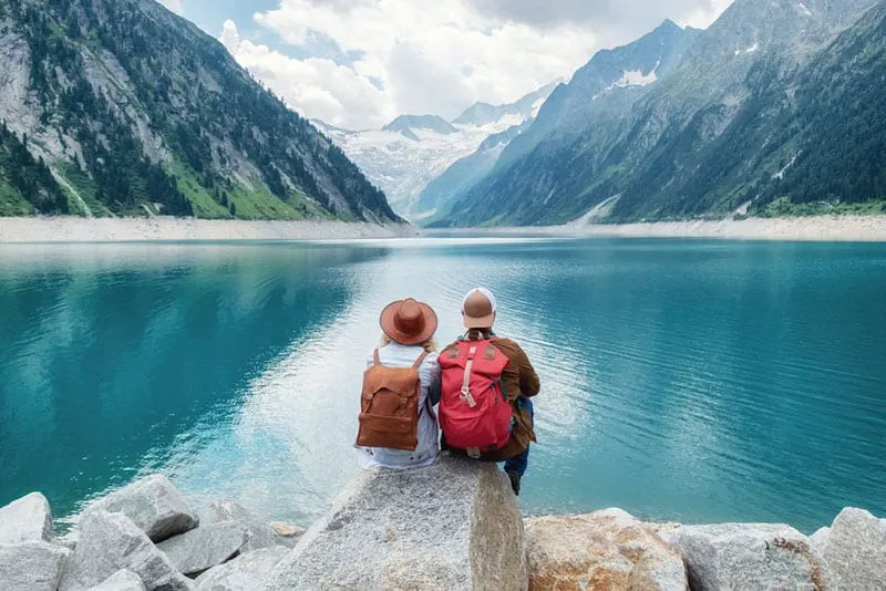 travel couple sitting in nature by the lake