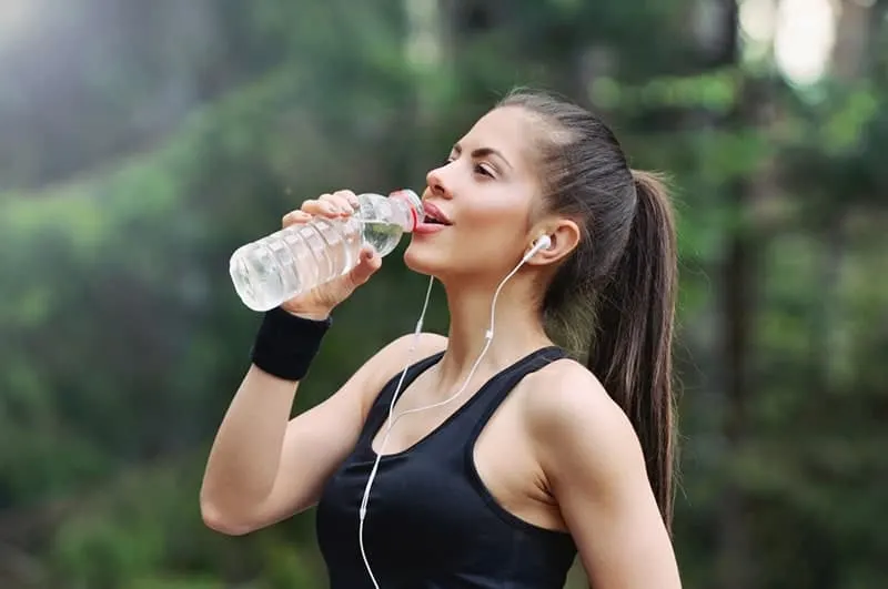 woman drinking water after running